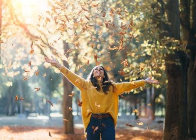Woman-tossing-leaves-in-the-air-in-the-sunlight